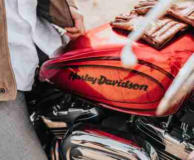 Photo of man sitting on an orange Harley Davidson.